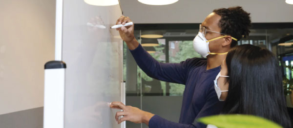 Masked workers at whiteboard